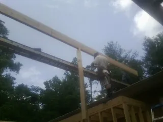 Carpenter setting a ridge beam over a new addition frame — Ice Dam Removal by Roofing Brothers in Hunter