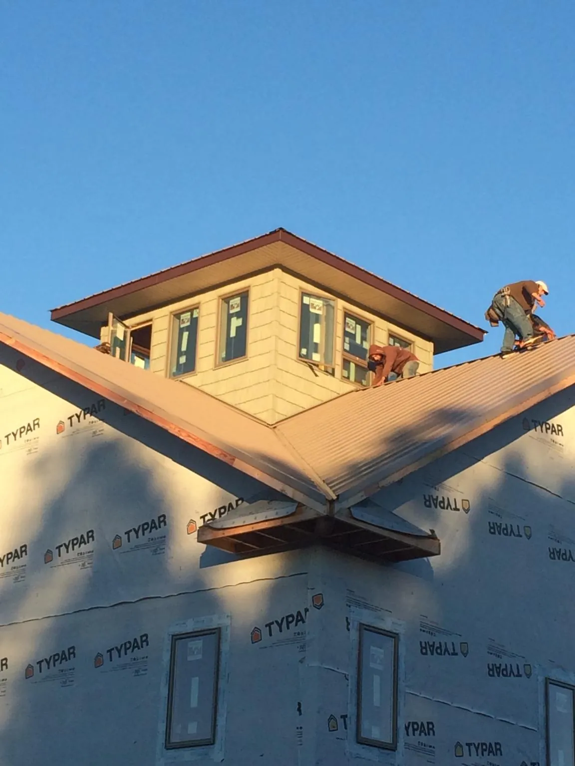Roofers working around a rooftop cupola on a new metal roof at sunset — Roof Waterproofing in Hunter by Roofing Brothers
